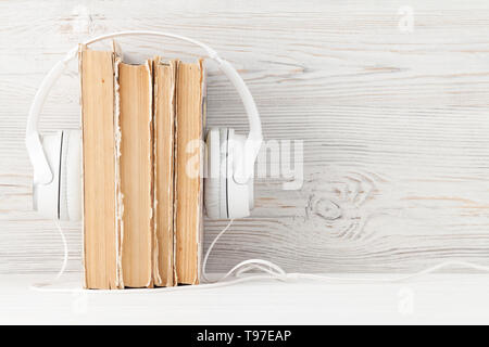 Home office workplace con la pila di libri vecchi e cuffie. Copia con lo spazio per il tuo testo. Libri Audio concept Foto Stock