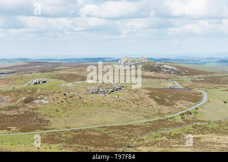 Da sinistra a destra una vista delle rocce Emsworthy, Sella e Tor Haytor attraverso la brughiera del Parco Nazionale di Dartmoor, Devon, Regno Unito, con una strada tortuosa. Foto Stock