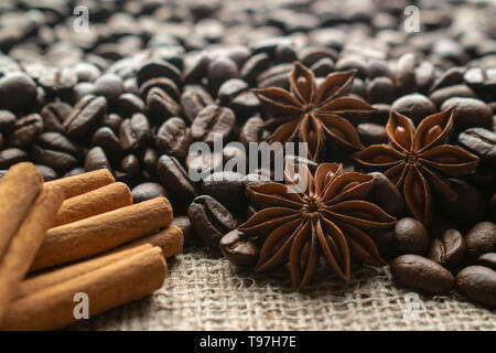 Caffè macinato per espresso con star aniseas e bastoncini di cannella sulla tela di luce Foto Stock
