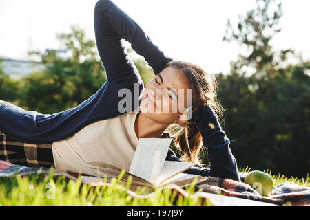 Bella ragazza teenae posa su un'erba all'aperto, studiare Foto Stock