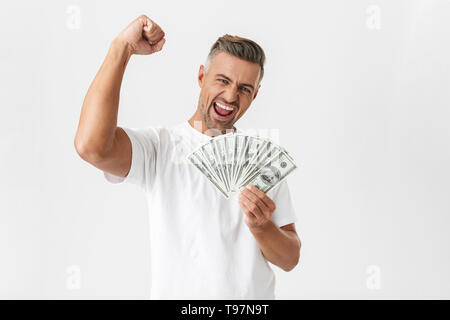 Immagine dell uomo unshaved 30s indossando t-shirt casual celebrando tenendo mucchio di soldi banconote isolate su sfondo bianco Foto Stock