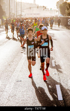 Mezza maratona di gettare ombre lunghe come escono dalla linea di partenza in Huntington Beach, CA, piombo da due concorrenti giapponesi. Foto Stock