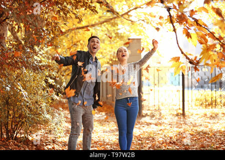 Felice coppia giovane giocando con foglie cadute in autunno park Foto Stock
