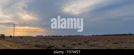 Maggio 2019, Burren Junction, Australia: il tramonto e la pioggia incombente nuvole sopra un grande piatto arata paddock su una siccità aziende agricole colpite in western NSW Foto Stock