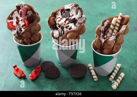 Bolla di deliziose cialde con gelato in coppe sulla tabella dei colori Foto Stock