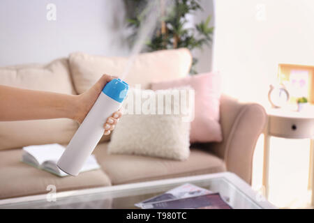 La donna la spruzzatura profumatore a casa Foto Stock