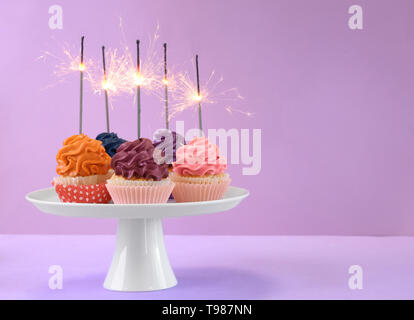 Stand con gustosi tortini di compleanno sul colore di sfondo Foto Stock