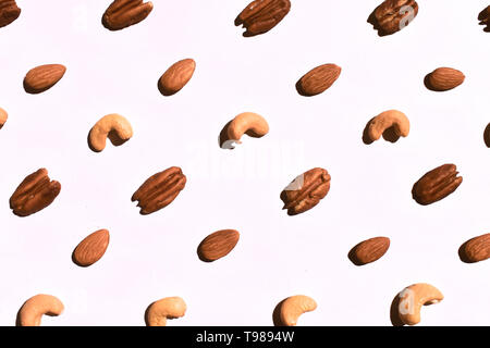 Dado di diverse varietà modello diagonale. Anacardi pelate mandorle noci pecan. Materie organiche dieta sana. Top da vicino la vista sullo sfondo bianco. Foto Stock