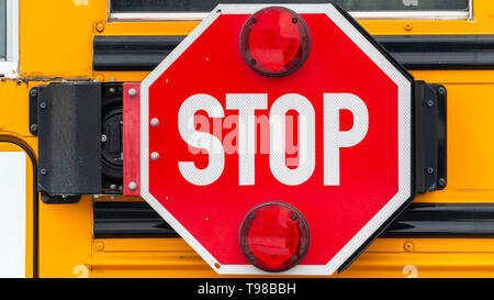Panorama Close up di un ottagono rosso a forma di stop con luci di segnale su un bus di scuola Foto Stock