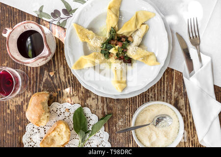 Cucina tipica italiana a. Casoncelli alla bergamasca (pasta farcita con briciole di pane, uova, parmigiano, carne di manzo macinata, salame) sulla piastra bianca nel resto locale Foto Stock