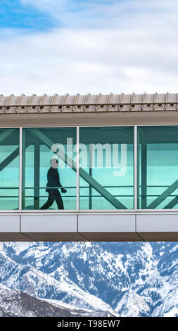 Chiara Silhouette verticale di un uomo a piedi all'interno di un ponte sopraelevato che collegano gli edifici Foto Stock