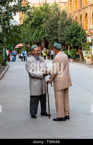 Aug 2017, Kashgar, Xinjiang, Cina: due locali uighur calorosamente gli uomini stringono le mani nelle strade di Kashgar Città Vecchia, una delle principali località turistica lungo la Via della Seta Foto Stock