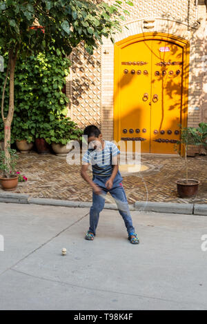 Aug 2017, Kashgar, Xinjiang, Cina: locale uighur bambino che gioca la filatura top nelle strade di Kashgar Città Vecchia, una delle principali località turistica lungo la Via della Seta Ro Foto Stock