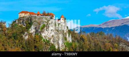 Castello medievale sulla cima di roccia al lago di Bled in Slovenia e in autunno la foresta di alberi Foto Stock