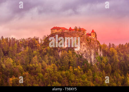 Castello medievale sulla cima di roccia al lago di Bled in Slovenia, autunno foresta di alberi e le nuvole colorate Foto Stock