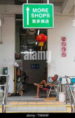 24.02.2019, Singapore , Singapore - un uomo più anziano si siede su una sedia a Singapore il quartiere di Chinatown e poggia. 0SL190224D016CAROEX.JPG [modello rele Foto Stock