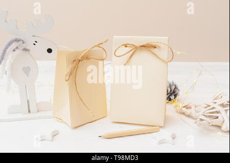 Mockup di due Natale regalo kraft pacchetti con tag su sfondo di legno. Vista superiore per il biglietto di auguri Foto Stock