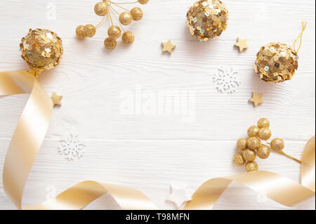 Sfondo di Natale per il biglietto di auguri con posto per testo. X-mas golden giocattoli e nastro beige su sfondo di legno. Piatto, laici top view photo mockup Foto Stock