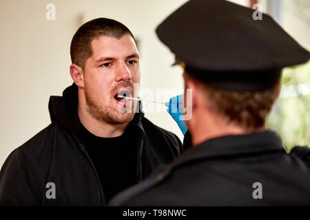Poliziotto tenendo campione di saliva nella cavità orale come un test del DNA Foto Stock