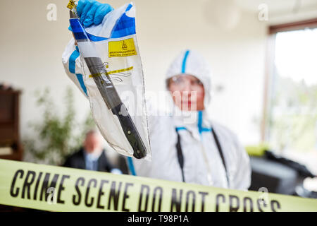 Polizia ufficiali forensi garantire coltelli a una scena del crimine Foto Stock