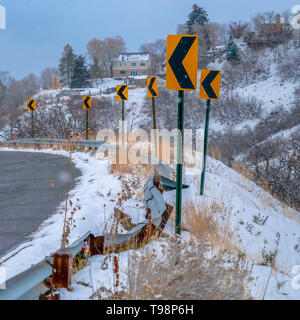 Strada innevata con indicazioni della strada in inverno Foto Stock