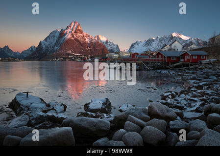 La luce del mattino illumina la coperta di neve Olstinden nel villaggio di pescatori di Reine, la Reine, Nordland, Norvegia Foto Stock