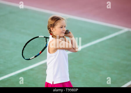 Bambino gioca a tennis sulla corte interna. Bambina con la racchetta e la palla in sport club. Esercizio attivo per i bambini. Attività estive per bambini. Foto Stock