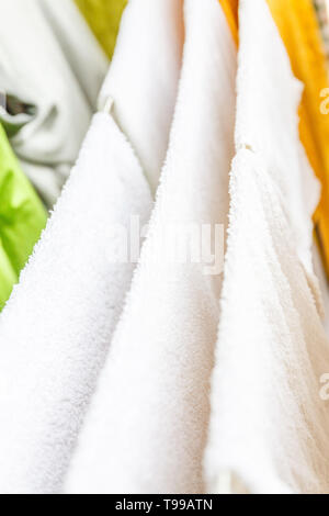 Bianche e colorate lenzuola e asciugamani per essere essiccato sul stendibiancheria. Foto Stock