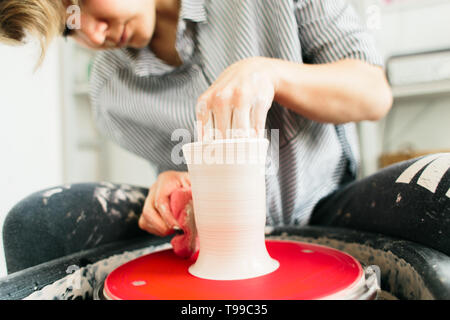 Le donne che lavorano sul tornio del vasaio. Mani scolpisce una coppa da pentola di creta. Workshop sulla modellazione sul tornio del vasaio. Foto Stock