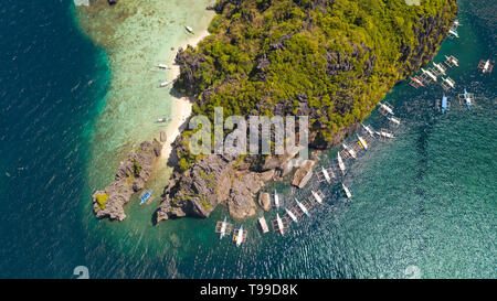 Isola tropicale con spiaggia bianca e barriera corallina.imbarcazioni turistiche nei pressi dell'isola. El Nido Palawan Parco Nazionale delle Filippine. Foto Stock