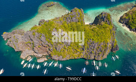 Isola tropicale con spiaggia bianca e barriera corallina.imbarcazioni turistiche nei pressi dell'isola. El Nido Palawan Parco Nazionale delle Filippine. Foto Stock
