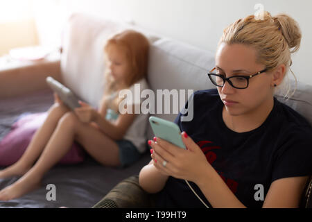 Donna e bambino guarda occupato con i gadget Foto Stock