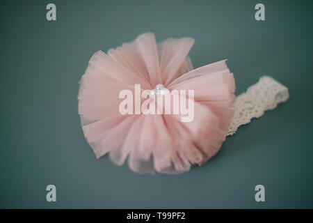 Lacy head band con grandi tulle rosa fiore con perle o un soft dusky pink head wrap insieme contro una vignetta sfondo teal Foto Stock