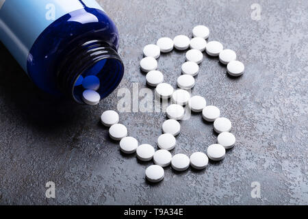 Pillole di bianco fuoriuscita da un flacone di farmaco formando un simbolo di dollaro Foto Stock