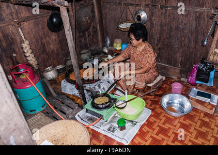 Una donna: la malese tradizionale cucinare frittelle nell'Iban casa etnica. Sarawak Foto Stock