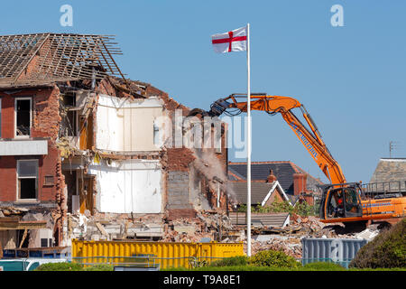 I lavori di demolizione in corso come the chadwick hotel sul lungomare di st annes on sea è ripartito sotto la sorveglianza della bandiera di San Giorgio Foto Stock