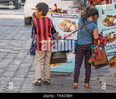 Un ragazzino e una bambina che vendono merci in una strada acciottolata a Panajachel, Guatemala Foto Stock