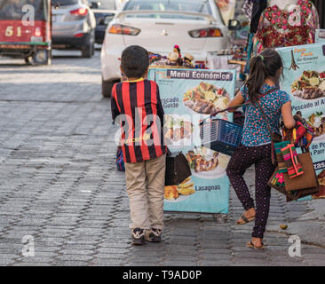 Un ragazzino e una bambina che vendono merci in una strada acciottolata a Panajachel, Guatemala Foto Stock