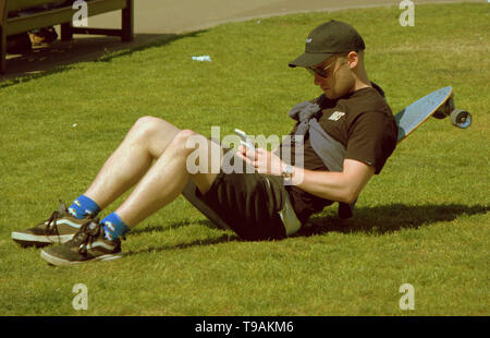 Glasgow, Scotland, Regno Unito, 17 maggio 2019, UK Meteo. Sunny scorcher di un giorno per la gente del posto e i turisti condividono l'erba con i piccioni nel centro civico della città George Square. Credito traghetto Gerard/Alamy Live News Foto Stock