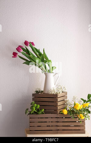 Vaso con splendidi tulipani e altri fiori su scatole di legno Foto Stock