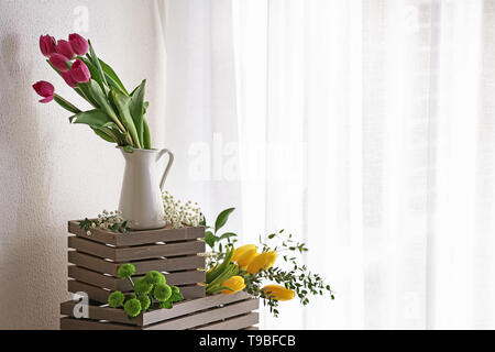 Vaso con splendidi tulipani e altri fiori su scatole di legno Foto Stock