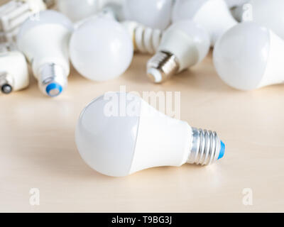 Una lampadina a LED luce nella parte anteriore del palo da varie lampade a basso consumo energetico su tavola Foto Stock