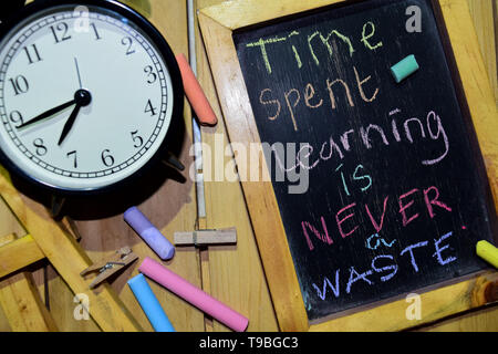 Il tempo speso per imparare non è mai uno spreco sulla frase manoscritta colorata sulla lavagna e sveglia con motivazione, ispirazione e concetti di istruzione. Foto Stock