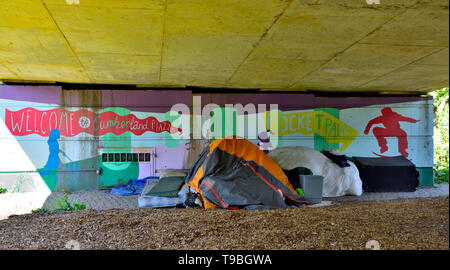 A pelo ruvido, senzatetto sotto un ponte con tenda e materassino Foto Stock