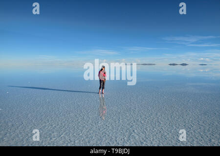 Tourist godendo il più grande del mondo di specchio, saline del Salar de Uyuni, Bolivia Foto Stock