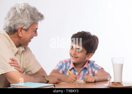 Nonno aiutando nipote in compiti Foto Stock