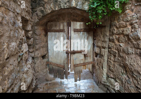 Vecchia porta di legno di un antico castello con una massiccia bullone di bloccaggio in un muro di pietra Foto Stock