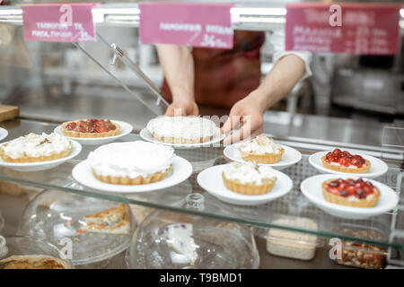 Vetrina con vari dolci di pasticceria e venditore sullo sfondo Foto Stock