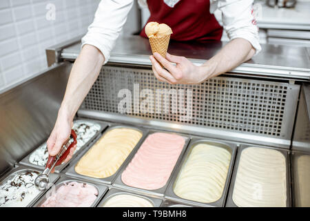 Vassoi di metallo piena di colorati gelato nella vetrina frigorifero, venditore tenuto gelati con convogliatore, vista da vicino Foto Stock