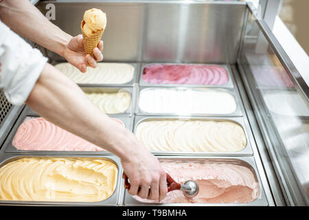 Vassoi di metallo piena di colorati gelato nella vetrina frigorifero, venditore tenuto gelati con convogliatore, vista da vicino Foto Stock